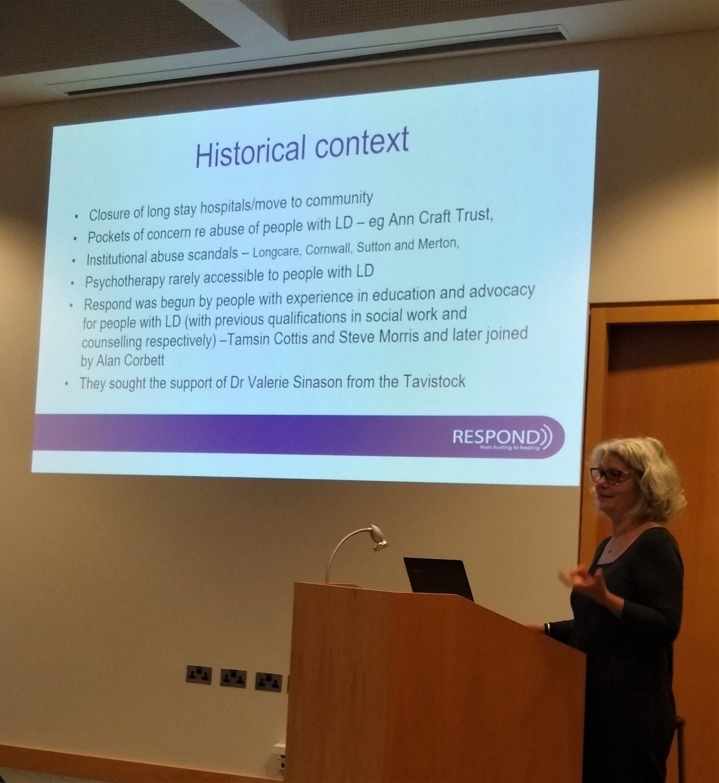 Noelle CE at AGM with screen showing history